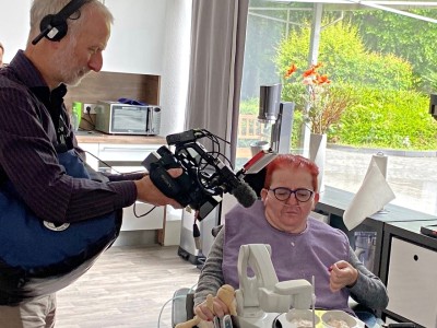 Filmteam dokumentiert assistiertes Essen bei einer Person mit Behinderung.
