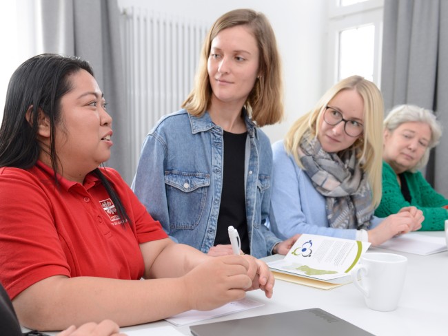 In einem Gespräch leitet eine Frau der Caritas anderen Personen an