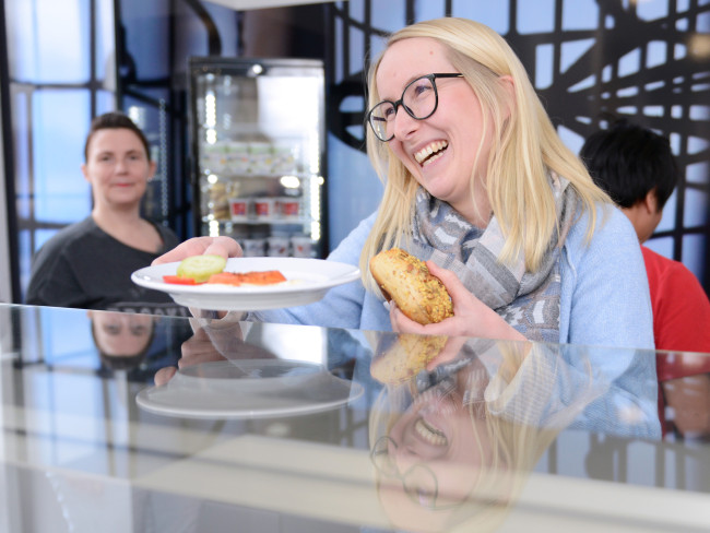 Eine Frau holt sich im St. Barbara Seminar & Hotel lächelnd ihr Frühstück ab