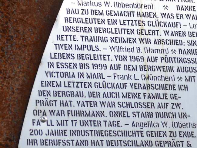 Nahaufnahme des Textes, der alle Bergleute würdigt und ihnen dankt. Der Text ist auf einer Skulptur angebracht, die vor der Licht und Lohnhalle steht.