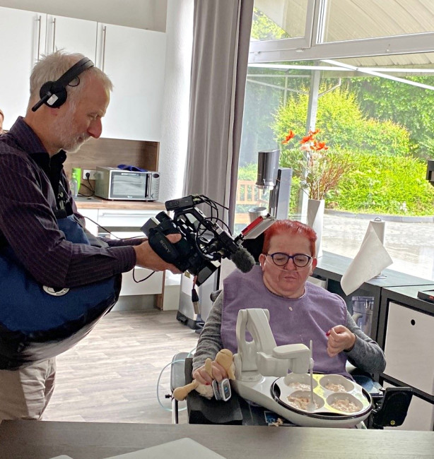 Filmteam dokumentiert assistiertes Essen bei einer Person mit Behinderung.